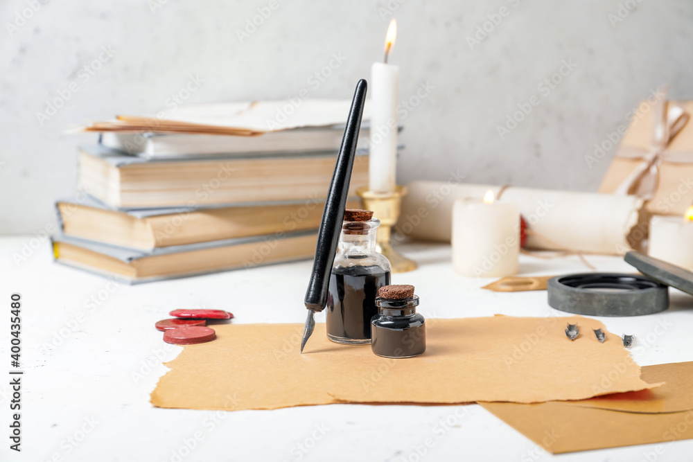 Composition with nib pen, paper sheets and inkwells on table