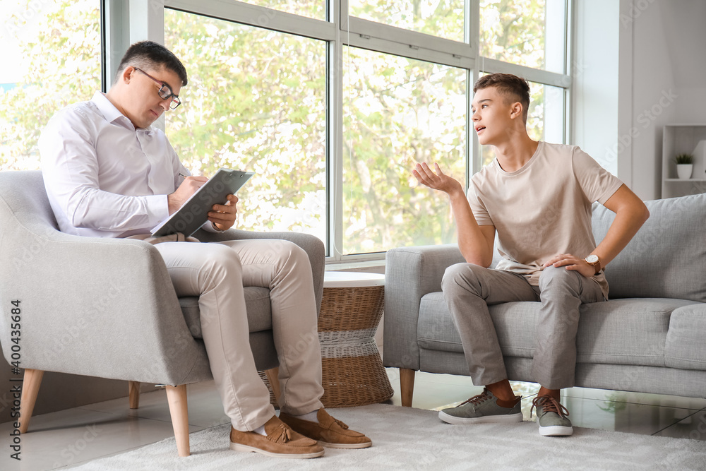 Psychologist working with teenage boy in office