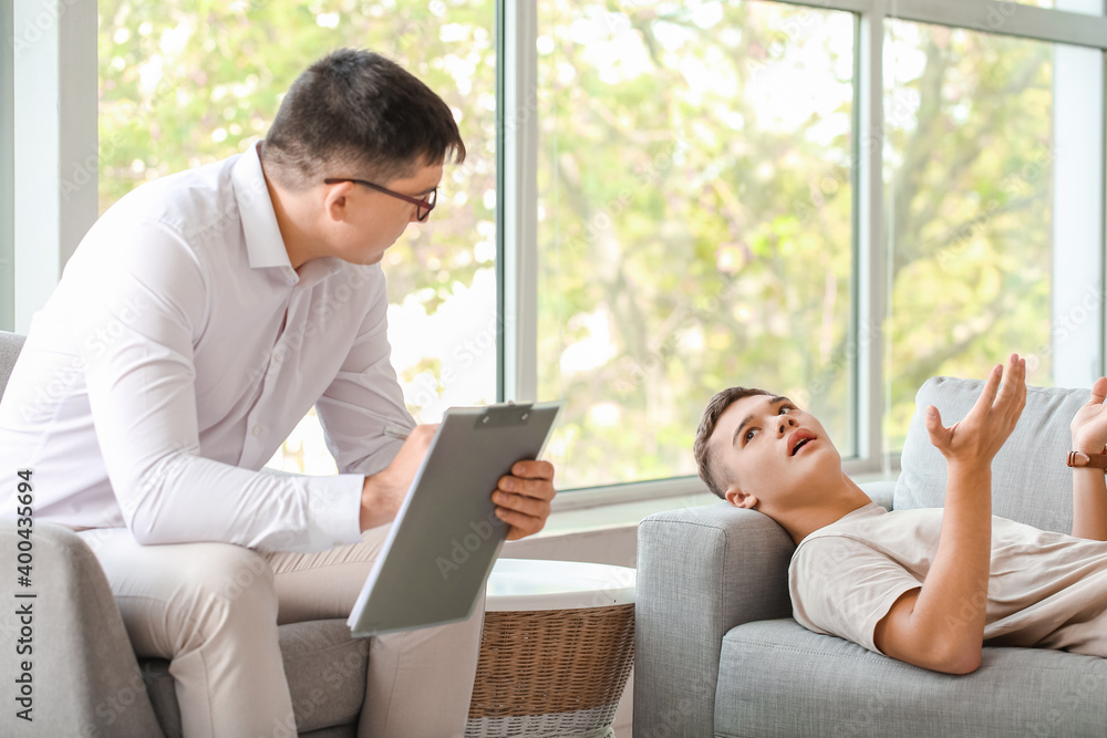 Psychologist working with teenage boy in office