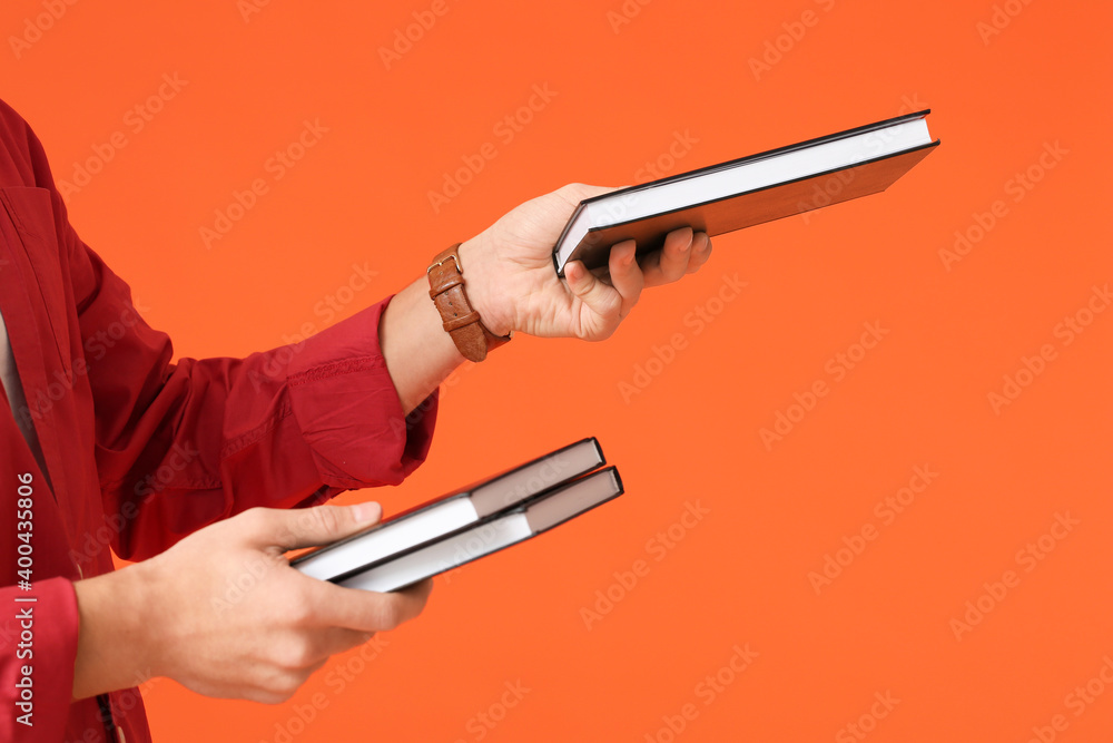 Teenage boy with books on color background, closeup