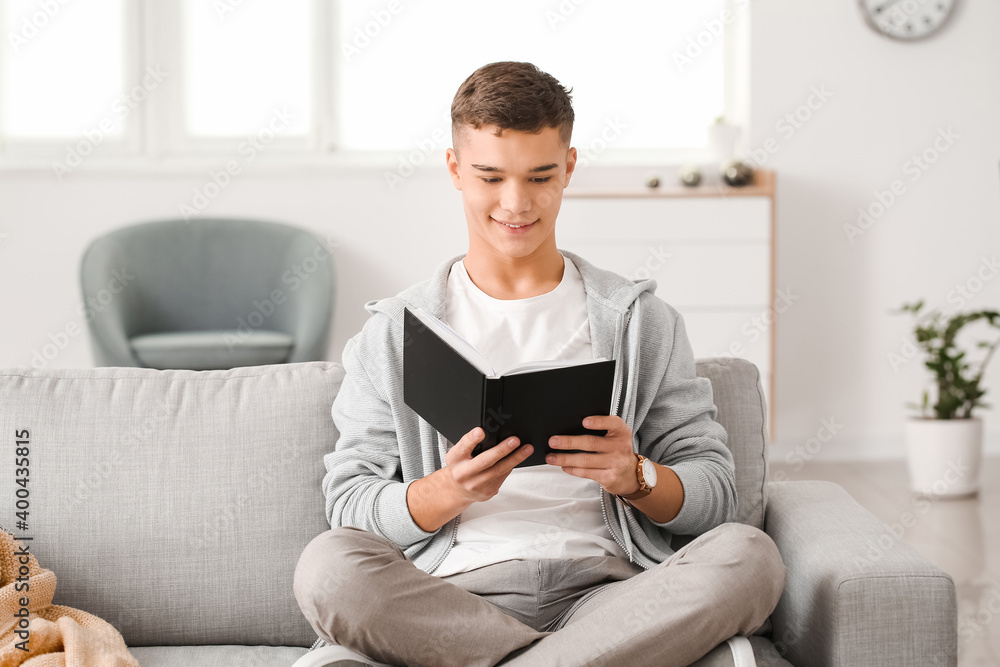 Teenage boy reading book at home