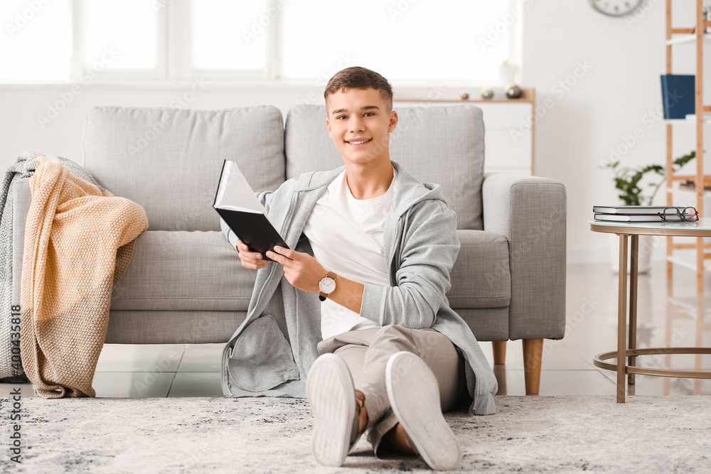 Teenage boy reading book at home