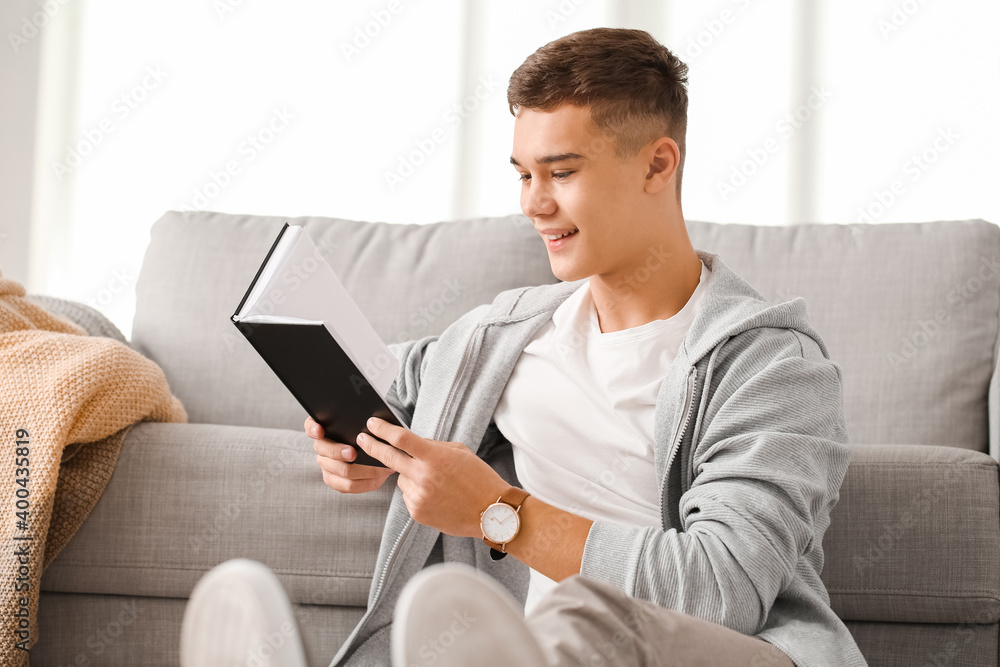 Teenage boy reading book at home