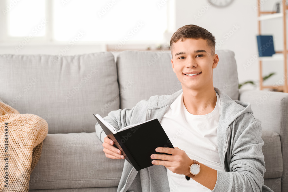 Teenage boy reading book at home