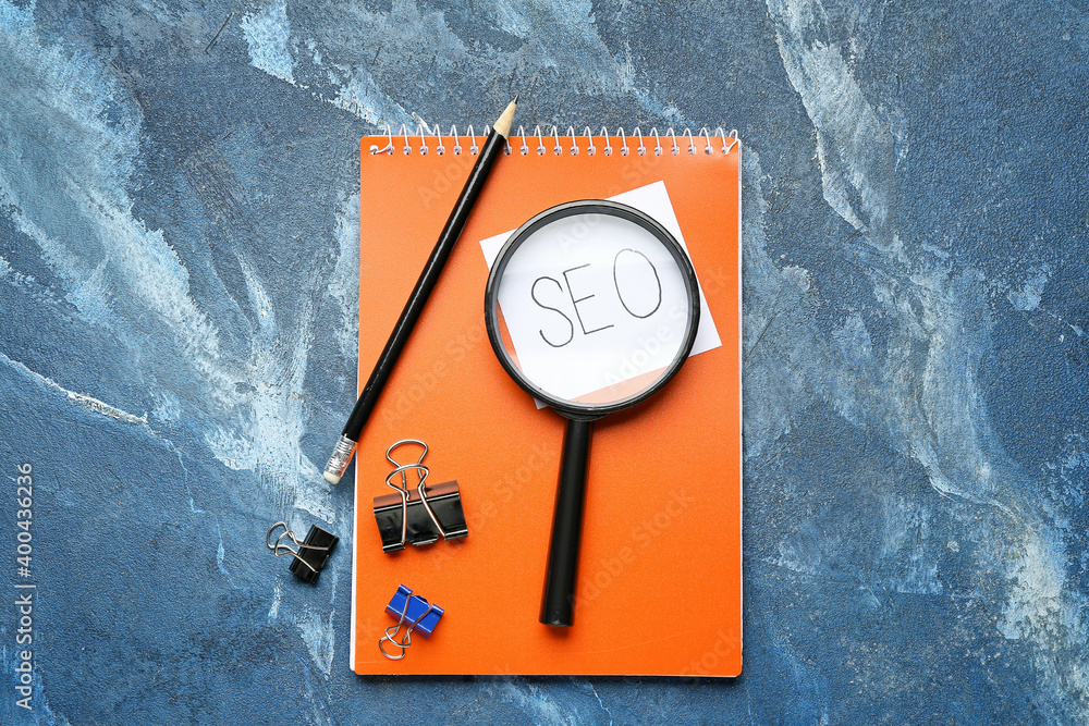 Abbreviation SEO with stationery and magnifier on color background