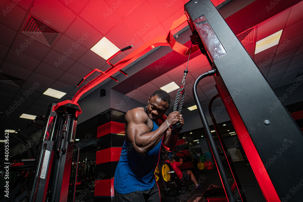 Athlete with strong body posing on gym background. Perfect man`s body. Heavy training in modern gym.