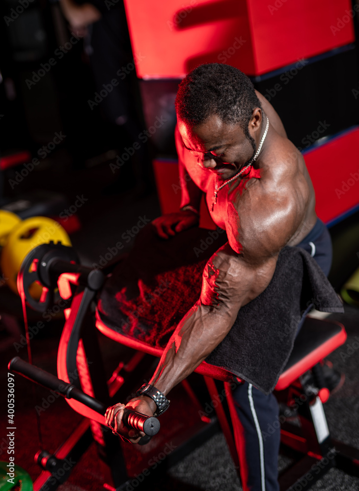 Athlete african american with strong body doing work out pushing up excercises in gym. View from the