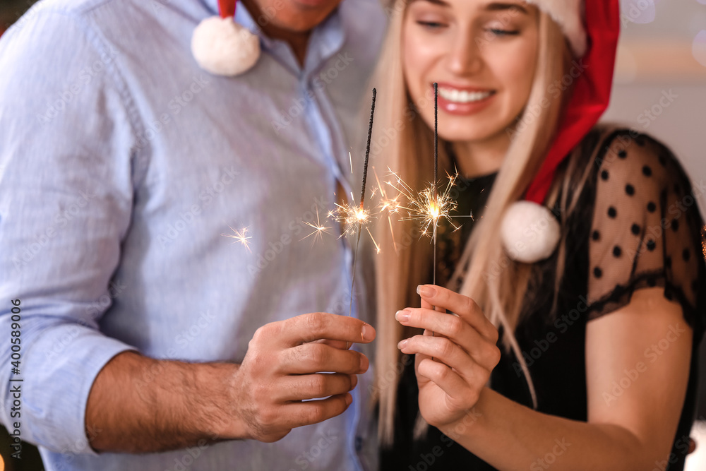 Happy young couple with sparklers celebrating Christmas at home