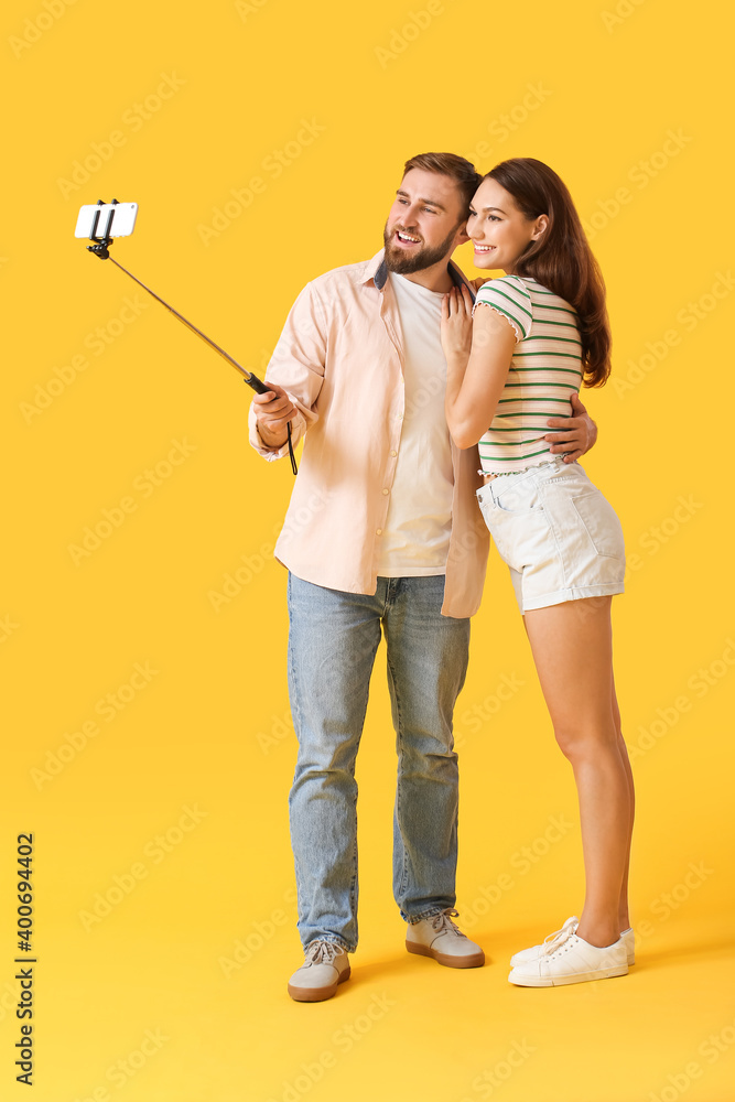 Young couple taking selfie on color background