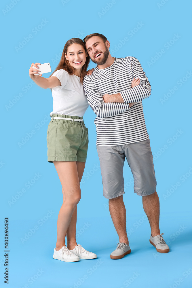 Young couple taking selfie on color background