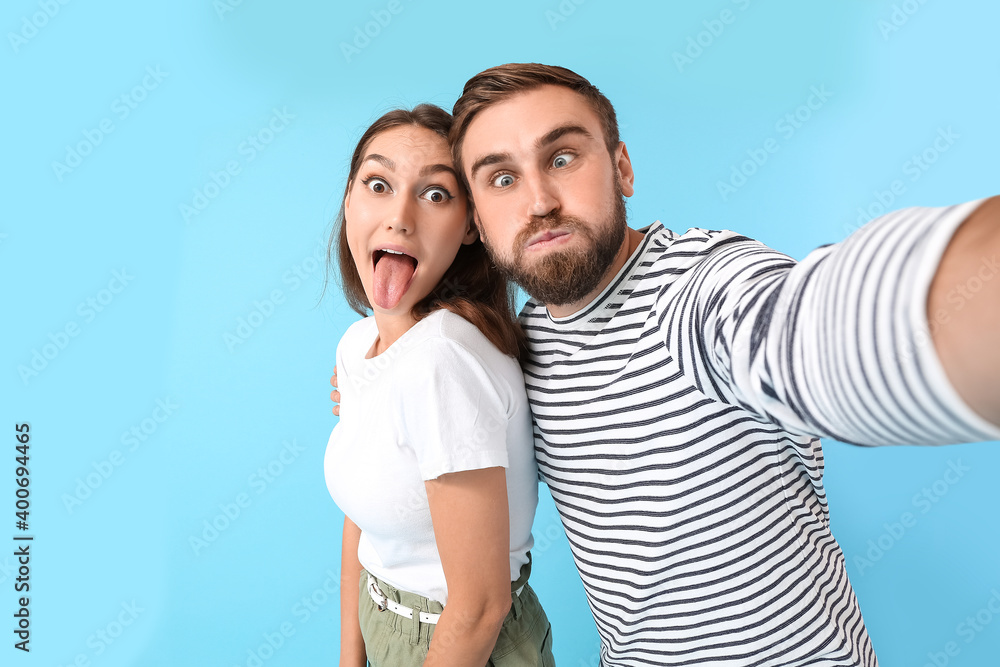 Young couple taking selfie on color background