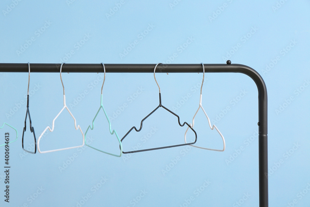 Rack with clothes hangers on color background