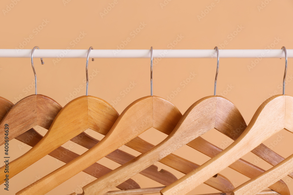 Rack with clothes hangers on color background, closeup