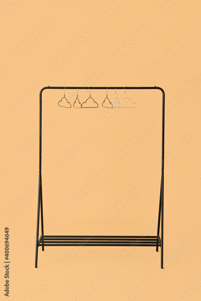 Rack with clothes hangers on color background