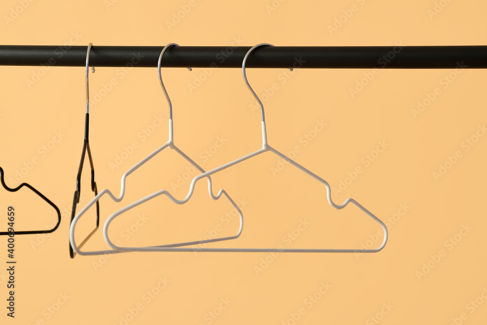 Rack with clothes hangers on color background