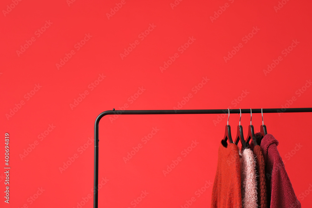 Rack with clothes on color background