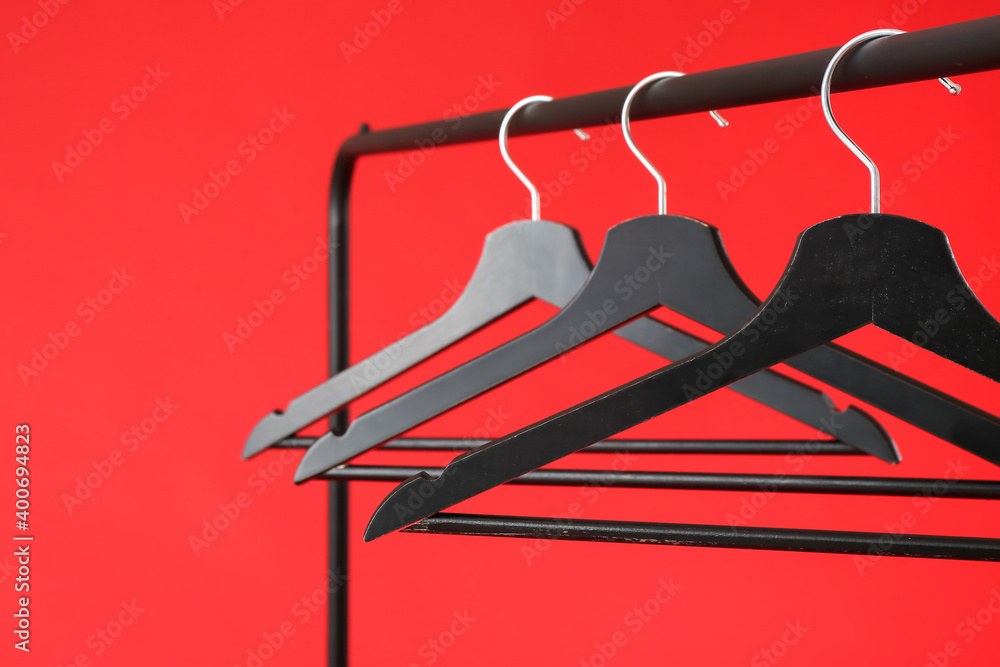 Rack with clothes hangers on color background