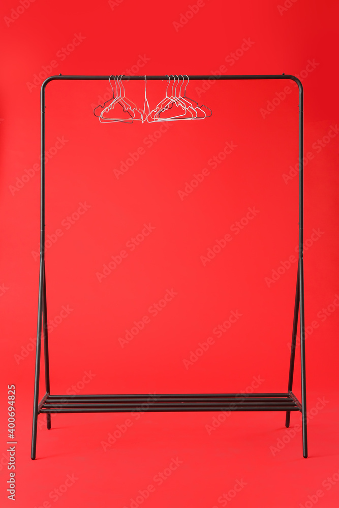 Rack with clothes hangers on color background