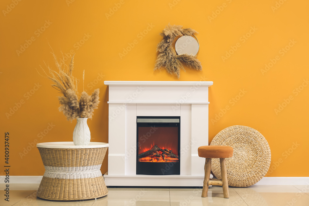 Fireplace with table and pouf in stylish interior of room