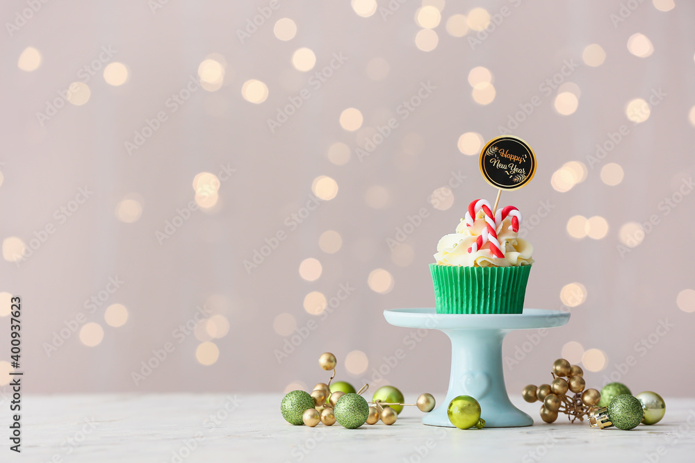 Dessert stand with tasty Christmas cupcake on blurred background