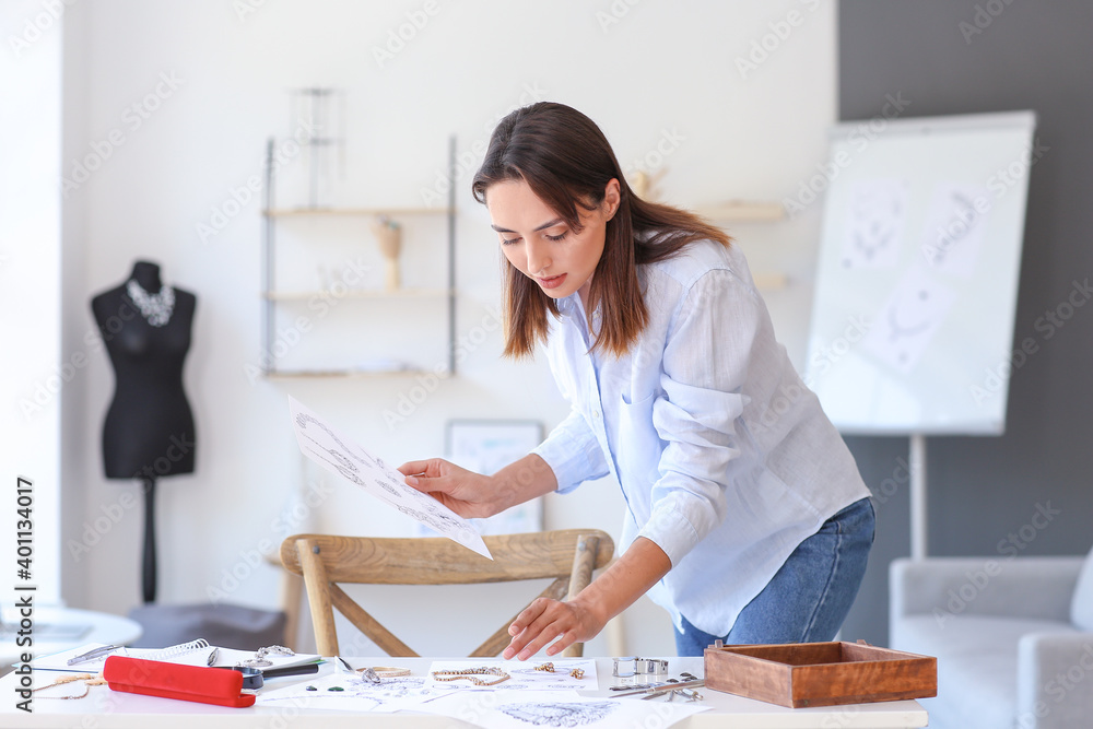 Female jewelry designer with sketches working in office