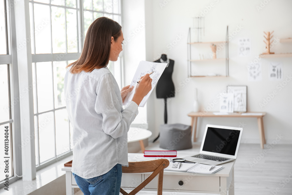 Female jewelry designer with sketches working in office