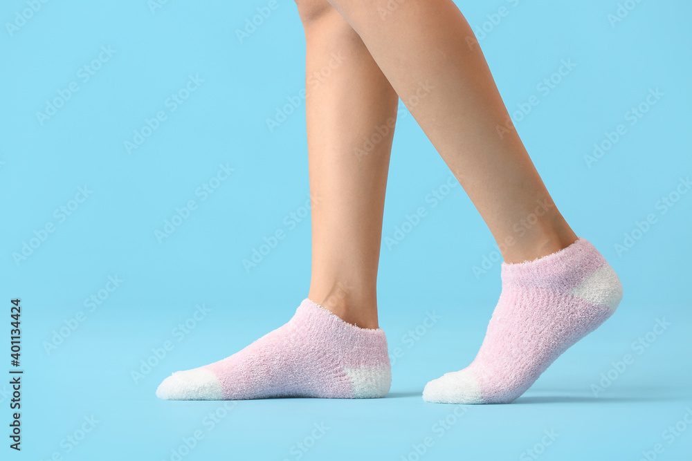 Legs of young woman in socks on color background