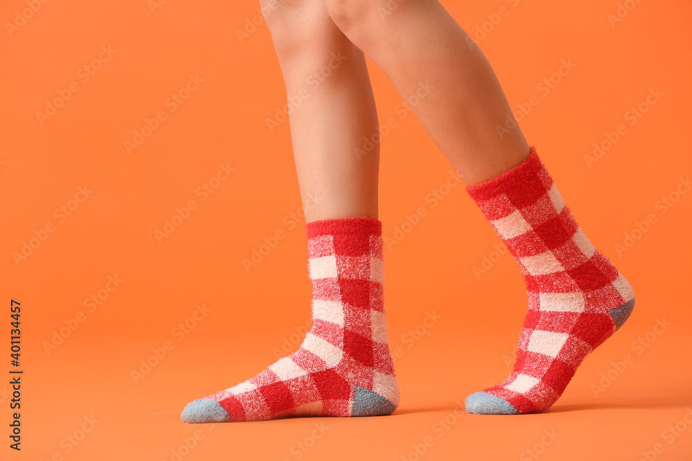 Legs of young woman in socks on color background