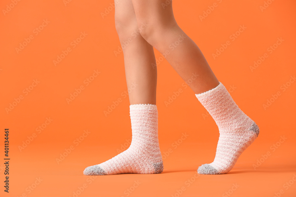 Legs of young woman in socks on color background