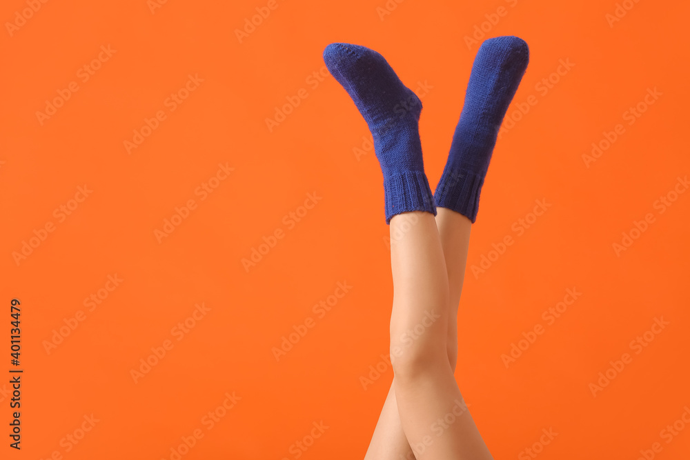 Legs of young woman in socks on color background