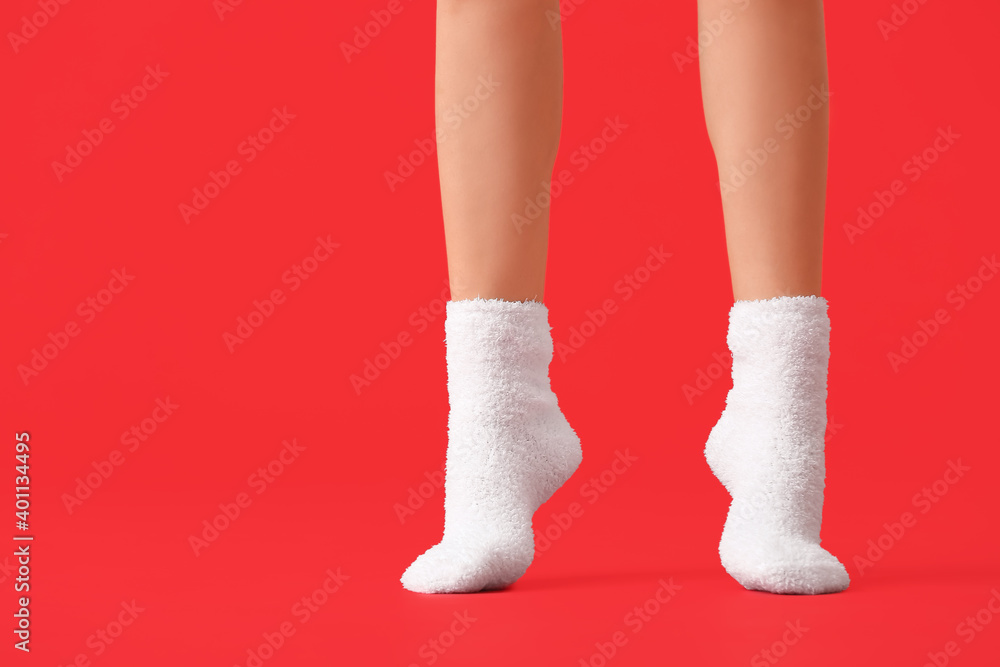 Legs of young woman in socks on color background