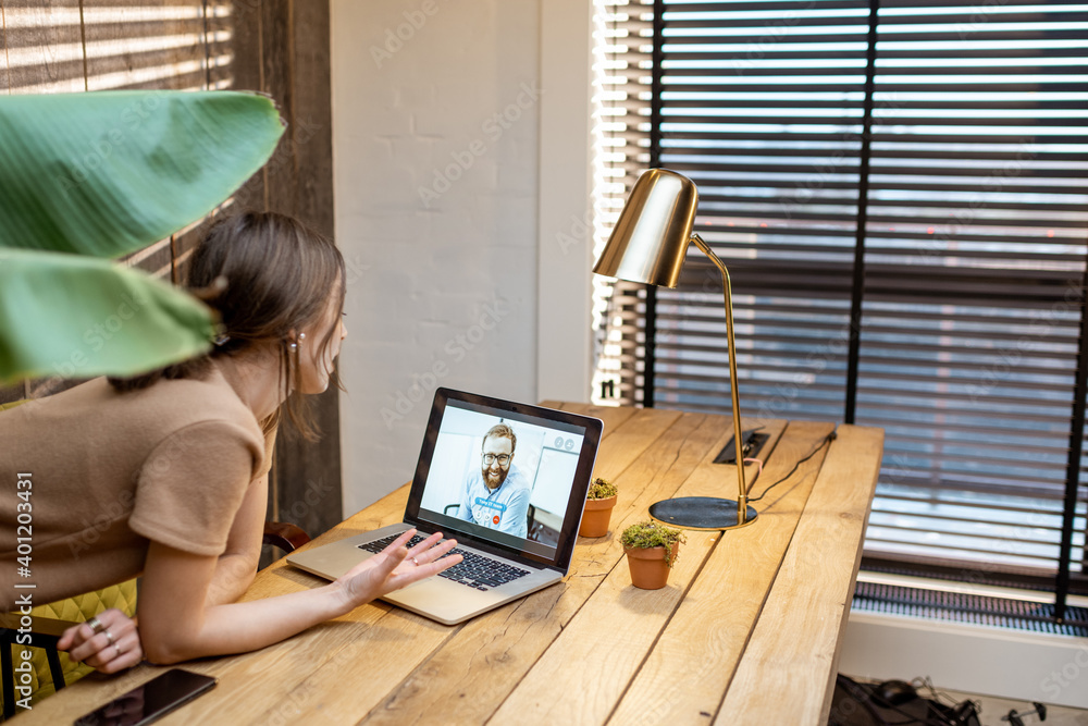 Young woman in domestic suit having a video connection with colleagues, working on laptop from a coz