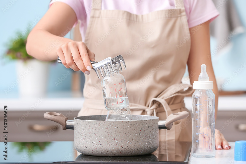 Woman cleaning baby bottle at home