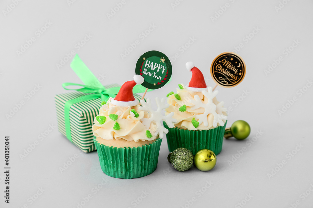 Tasty Christmas cupcakes on light background