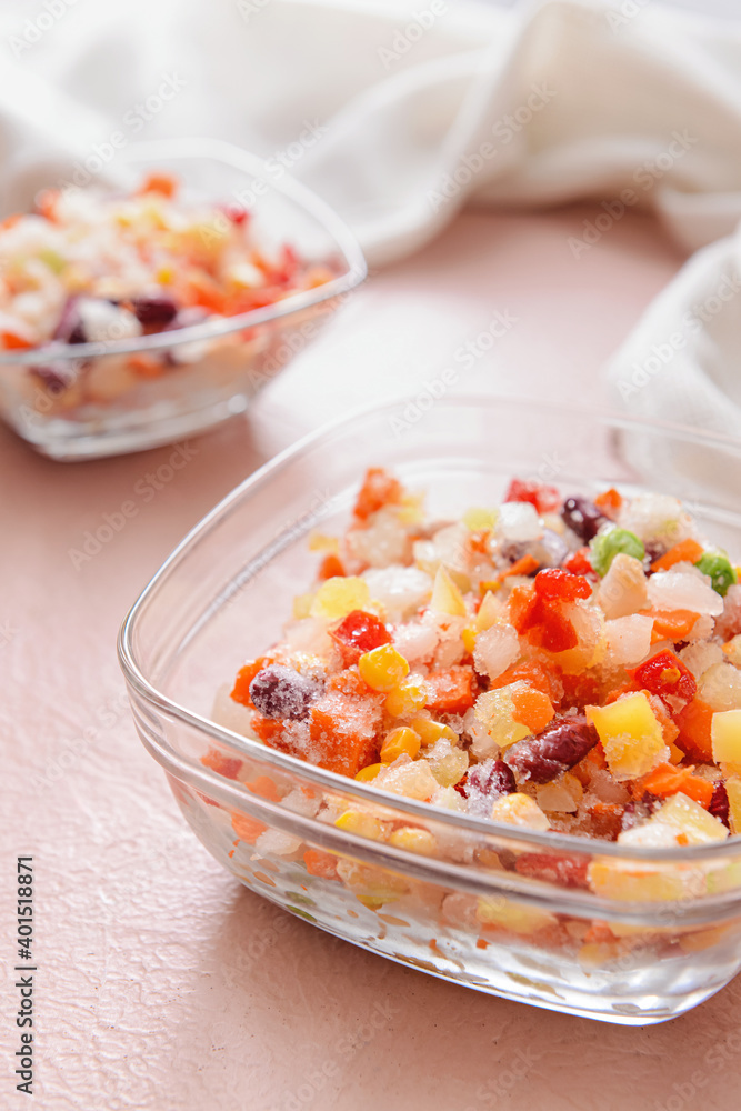 Frozen vegetables in bowls on color background