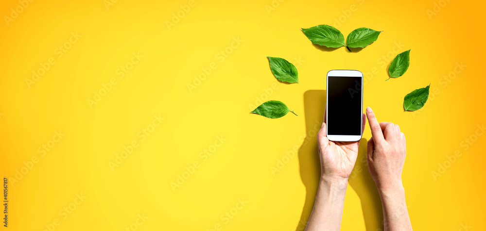 Person holding a smartphone with green leaves