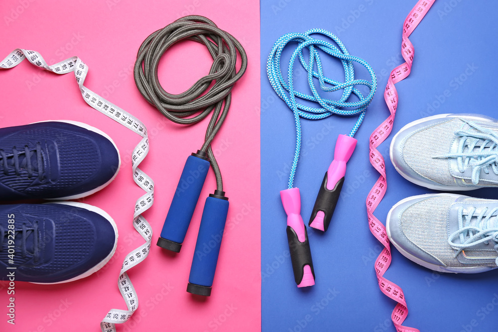 Male and female sportive shoes and jumping ropes on color background