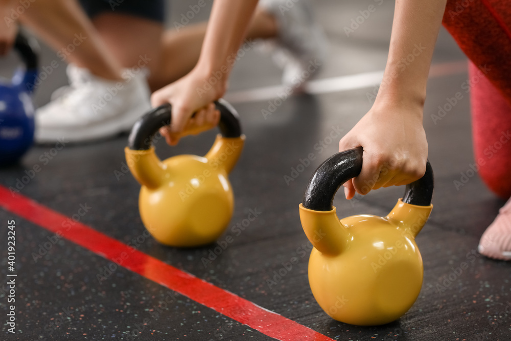 Sporty people exercising with kettlebell in gym