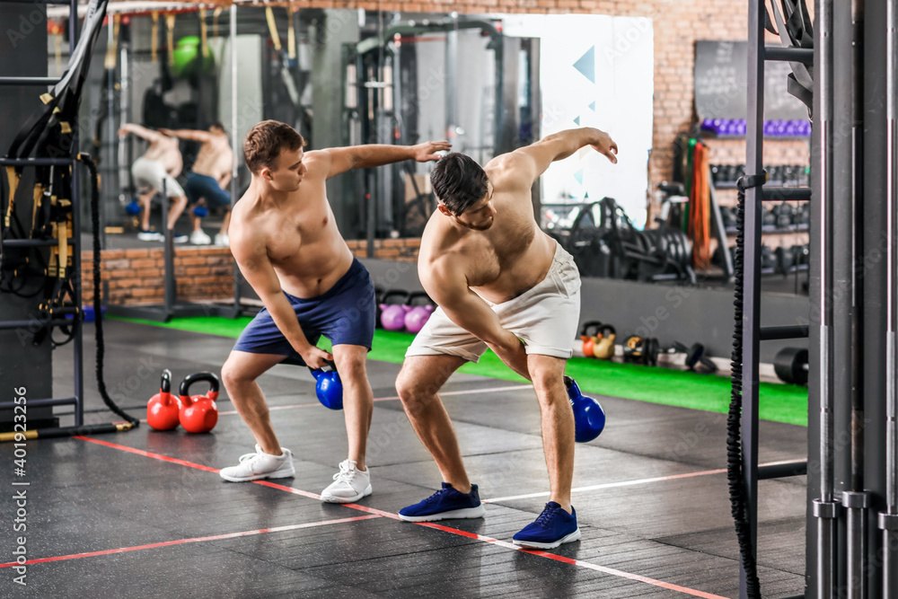 Handsome muscular men exercising with kettlebell in gym