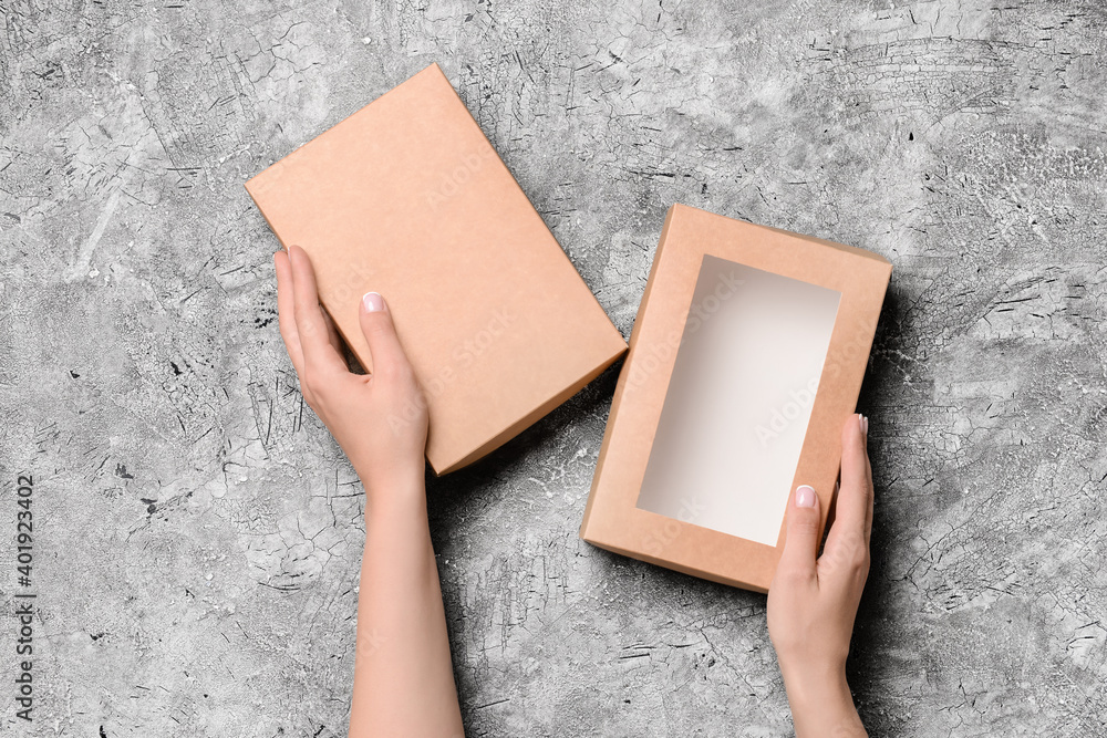 Hands with cardboard box on dark background