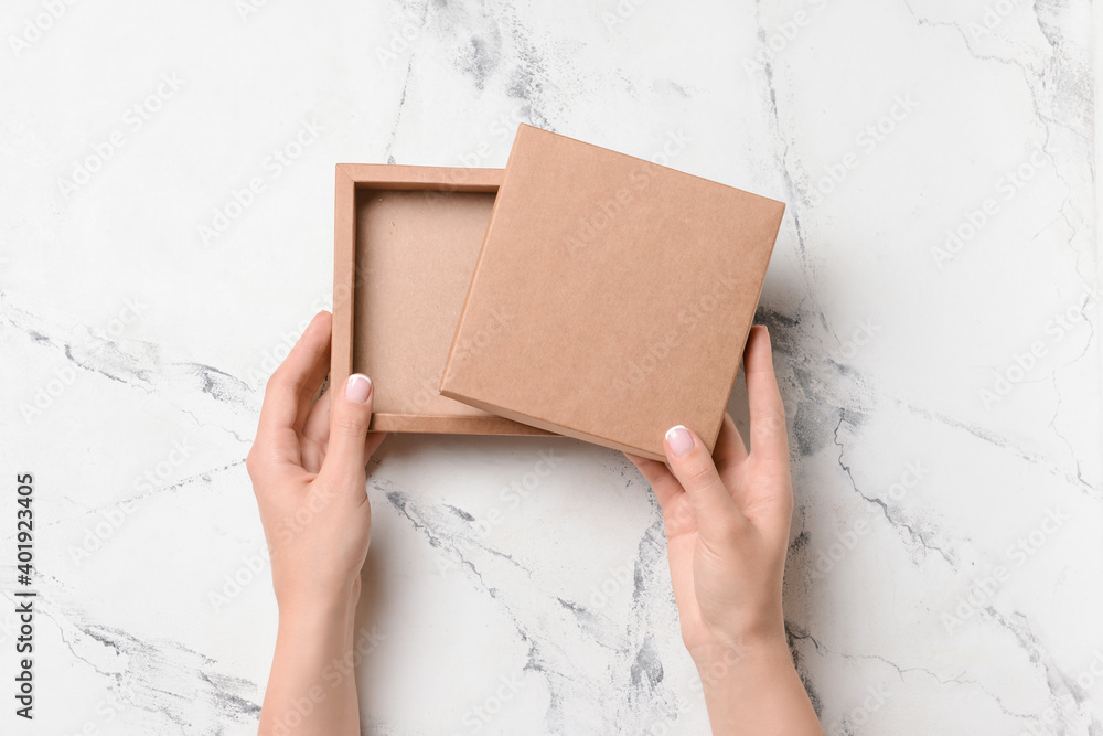 Hands with cardboard box on light background