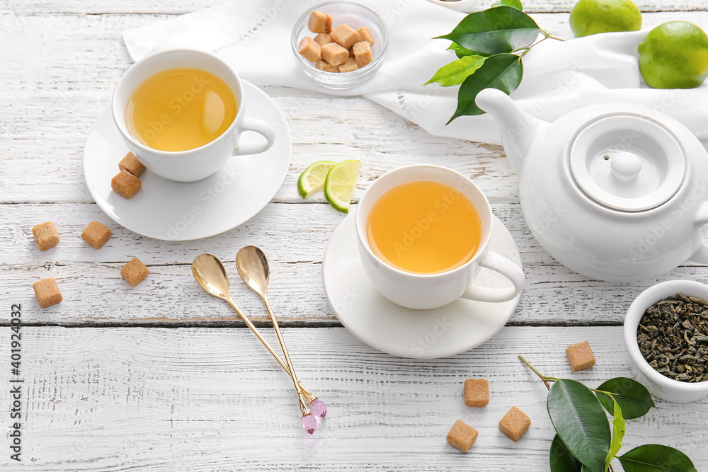 Composition with cups of green tea and lime on table