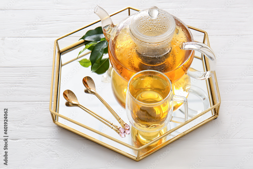 Tray with cup of green tea and teapot on table