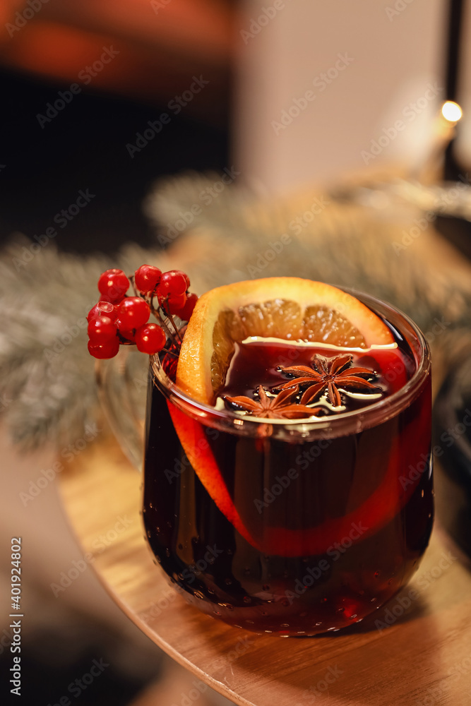 Glass of tasty mulled wine near fireplace