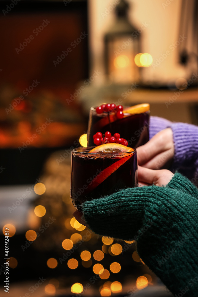 Women with tasty mulled wine near fireplace