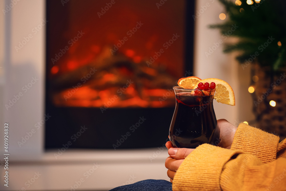 壁炉旁的女人拿着美味的热葡萄酒