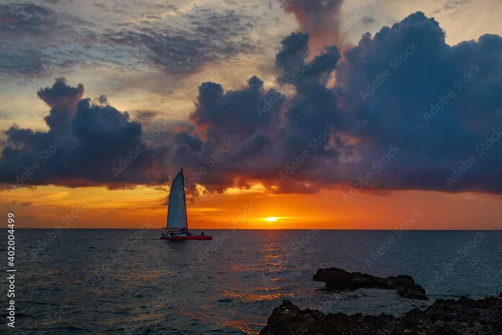 Spectacular bright red sunset on the sea with a sailboat visible