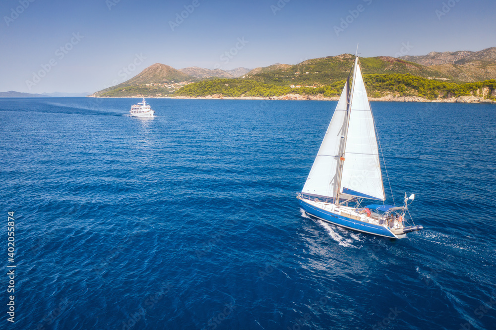 Aerial view of beautiful white sailboat in blue sea at bright sunny summer evening. Adriatic sea in 