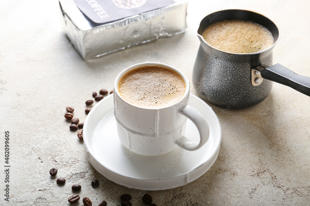 Cup and pot with hot aromatic coffee on table