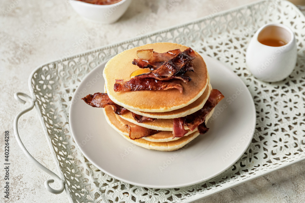 Plate of tasty pancakes with fried bacon on table